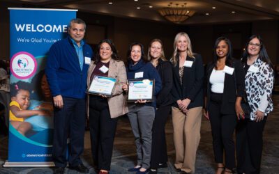 Hospital champions stand together, smiling and accepting the 2025 OBI award, with the award visible in their hands.